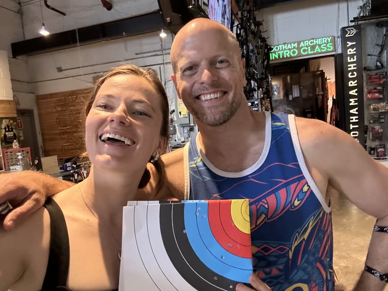 Val and Tim Ferriss holding a paper target at Gotham Archery